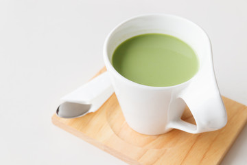 cup of hot milk green tea on white table