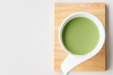 cup of hot milk green tea on white table