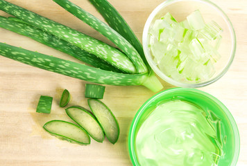 the sliced and leaf of fresh aloe vera with aloe vera gel product on  wooden plate , natural clear gel as the star beauty ingredient  for skin care