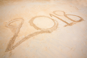 Year 2018 written at the sand beach with sea wave water