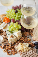 Cheese plate served with grapes, jam, cured melon, crackers and nuts