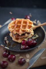 Honey on waffles with cherry berries on dark wooden background. breakfast concept