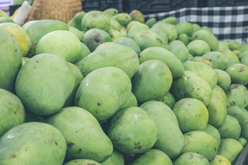 Tropical fruits close up green mangoes in the asian shop. Bali island, Indonesia. Organic market.