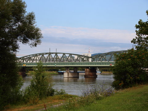 Green Metal Railway Steel Bridge viewed from Park near Donau