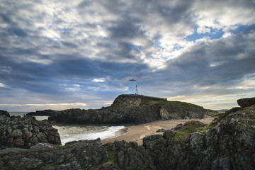Fototapeta na wymiar Stunning Twr Mawr lighthouse landscape from beach with dramatic sky and cloud formations