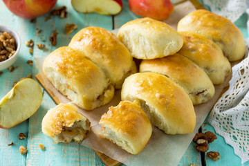 Homemade apple pies with fresh apples and walnuts from yeast dough on a kitchen wooden table. Apple patties on the table in a rustic style.