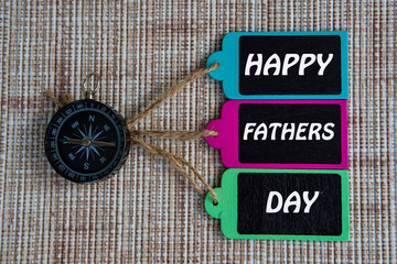 HAPPY FATHERS DAY inscription written on paper tag, compass on old wooden background.