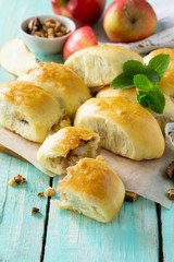 Homemade apple pies with fresh apples and walnuts from yeast dough on a kitchen wooden table. Apple patties on the table in a rustic style.