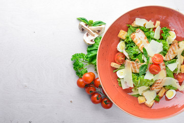 Fototapeta na wymiar Caesar salad with chicken and fresh vegetables. On a wooden background. Top view. Free space for your text.