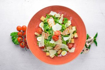 Caesar salad with chicken and fresh vegetables. On a wooden background. Top view. Free space for your text.