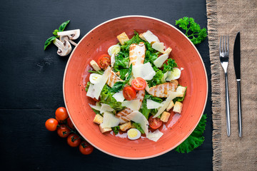 Caesar salad with chicken and fresh vegetables. On a wooden background. Top view. Free space for your text.