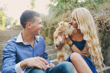 the guy and the girl at a romantic meeting, walk with spitz-dog in the summer garden