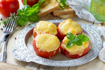 Stuffed tomatoes. Tomatoes baked with cheese and chicken on a wooden kitchen table.