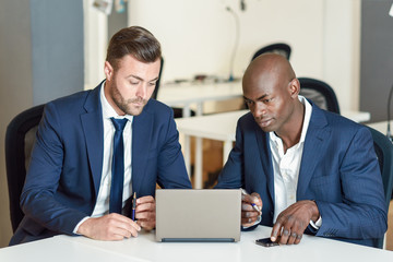 Black and caucasian businessmen looking at a laptop computer
