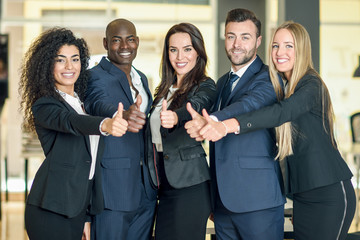 Group of businesspeople with thumbs up gesture in modern office.