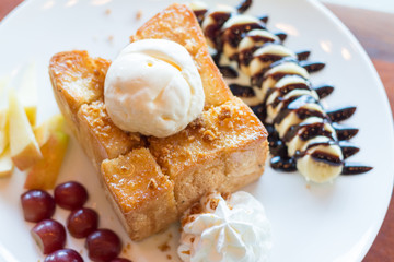 Honey toast with vanilla ice cream, whipped cream and chocolate syrup. Served with banana, grape and apple(selective focus)