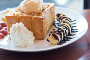 Honey toast with vanilla ice cream, whipped cream and chocolate syrup. Served with banana, grape and apple(selective focus)