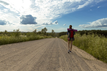 Obraz premium Young woman with backpack hiking in the countryside. Stress free travel concept. 