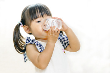 コップでミルクを飲む幼い女の子