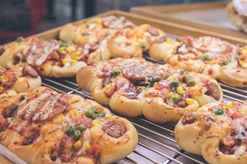 Mini pizzas with cheese, tomato, green beans, corn and sausages in the shoppin mall, small italian bakery. Tropical island of Bali, Indonesia.