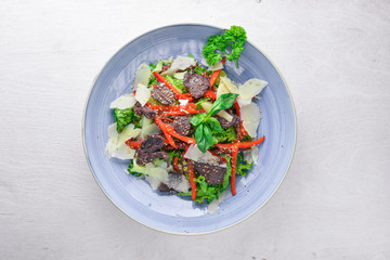 Veal and fresh vegetables salad. On a wooden background. Top view. Free space for your text.