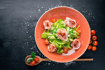 Salad of fresh vegetables and bacon. Caesar. On a wooden background. Top view. Free space for your text.