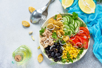 Summer Salad with vinaigrette salad dressing. Salad with tuna, fresh vegetables, pistachios and greens on a gray stone background or slate. Top view. Copy space.