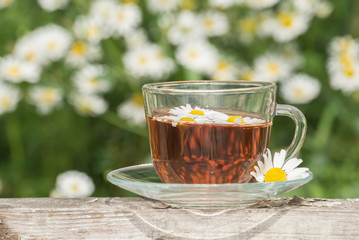 Herbal tea with chamomile on a wooden table on a summer sunny morning