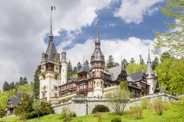 Fototapeta na wymiar Beautiful view of the famous Peles Castle, Sinaia, Romania, with the Romanian flag flying on top of a spire