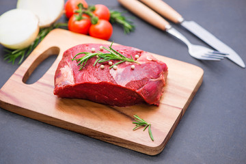 Raw beef on a cutting board  with spices and ingredients for cooking.