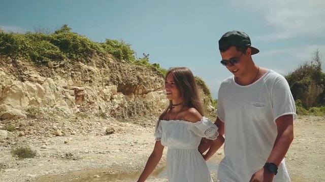 Romantic young couple walking together on shore cliff on a sunny summer day with blue skyin slow motion, Bali. Shot with sony a7s on a motorized 3-axis handheld gimbal.