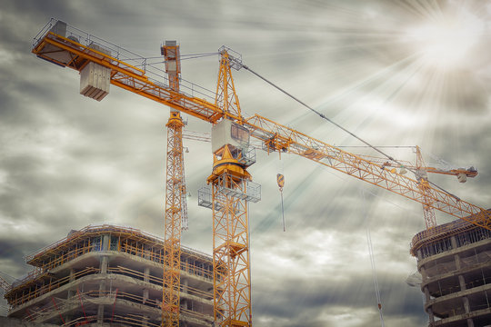 Crane on construction site near concrete buildings. Concept of construction close-up