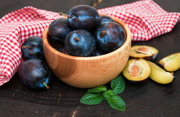Bowl with  plums with green leaves