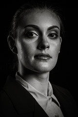 Naklejka na ściany i meble Dramatic portrait of businesswoman in studio on black background in black an white