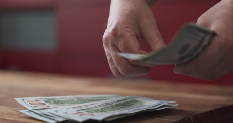 Obraz premium side shot of woman counting dollars on wood table