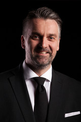 Portrait of adult confident businessman in studio photo on black background
