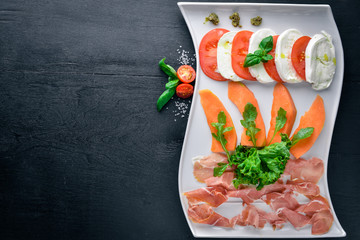 Carpaccio with tomatoes and mozzarella cheese. On a wooden background. Top view. Free space for...