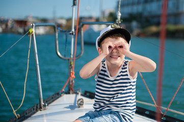 happy little boy captain on a luxury boat in the summer