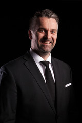 Portrait of adult confident businessman in studio photo on black background