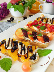 Bruschetta with berries, fruits and cream cheese on a white plate. Italian meal