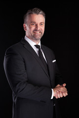 Portrait of adult confident businessman in studio photo on black background