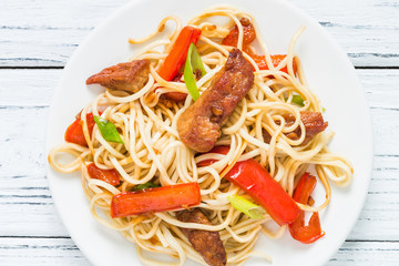 Szechuan stir fried spicy pork with red pepper and green onion. Chinese food or Asian cuisine concept on white wooden table. Top view, close up