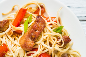 Szechuan stir fried spicy pork with red pepper and green onion. Chinese food or Asian cuisine concept on white wooden table. Top view, close up