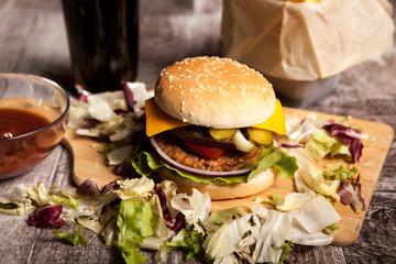 Delicious home made burgers on wooden plate next to a glass of cola and fries. Fast food. Unhealthy snack