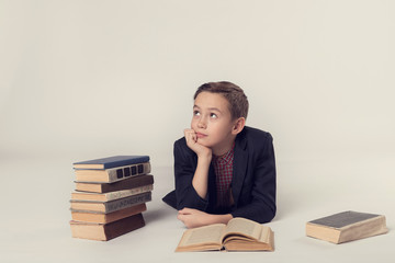 Young schoolboy daydreaming on a grey background.