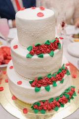 White wedding cake on wedding banquet with red rose and other flowers