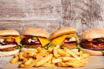 Tasty home made cheeseburgers on wooden plate next to fries. Fast food. Unhealthy snack