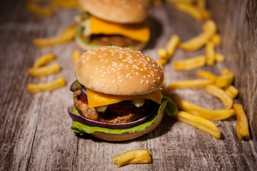 Classic home made burgers on wooden plate next to fries. Fast food. Unhealthy snack