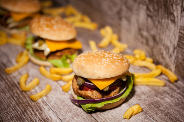 Classic home made burgers on wooden plate next to fries. Fast food. Unhealthy snack