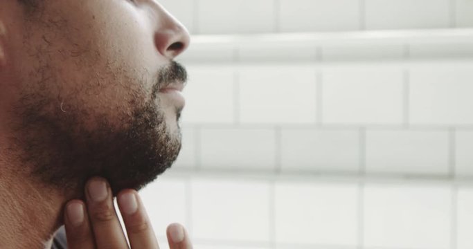 mixed race man touches his face and beard before shaving